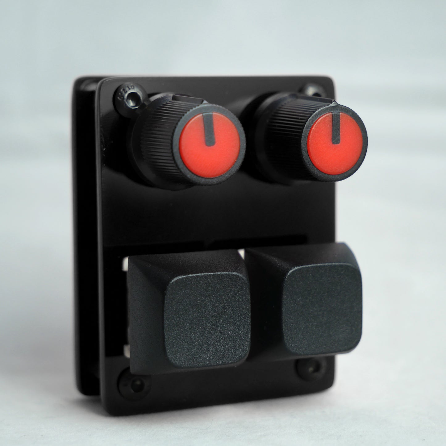 Black control panel with red knobs and gray buttons on a light gray background